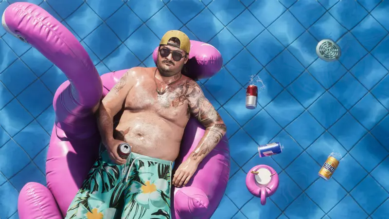 Cal Hampton floating on a pink flamingo pool float with a can of beer