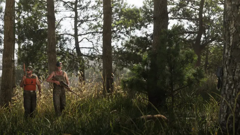 Two hunters carrying rifles through the Mount Kalaga woods