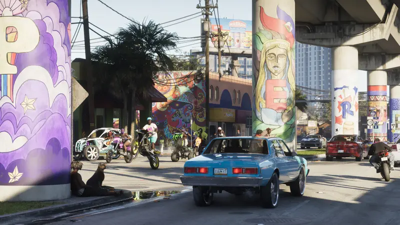 A lowrider and bikes under a mural-covered overpass